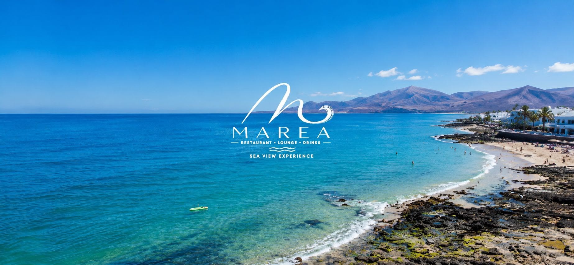 Costa de Puerto del Carmen con el mar turquesa, la playa y las montañas al fondo, y el logotipo de Marea